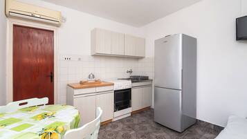 A compact kitchen with a refrigerator, oven, and a wooden countertop.