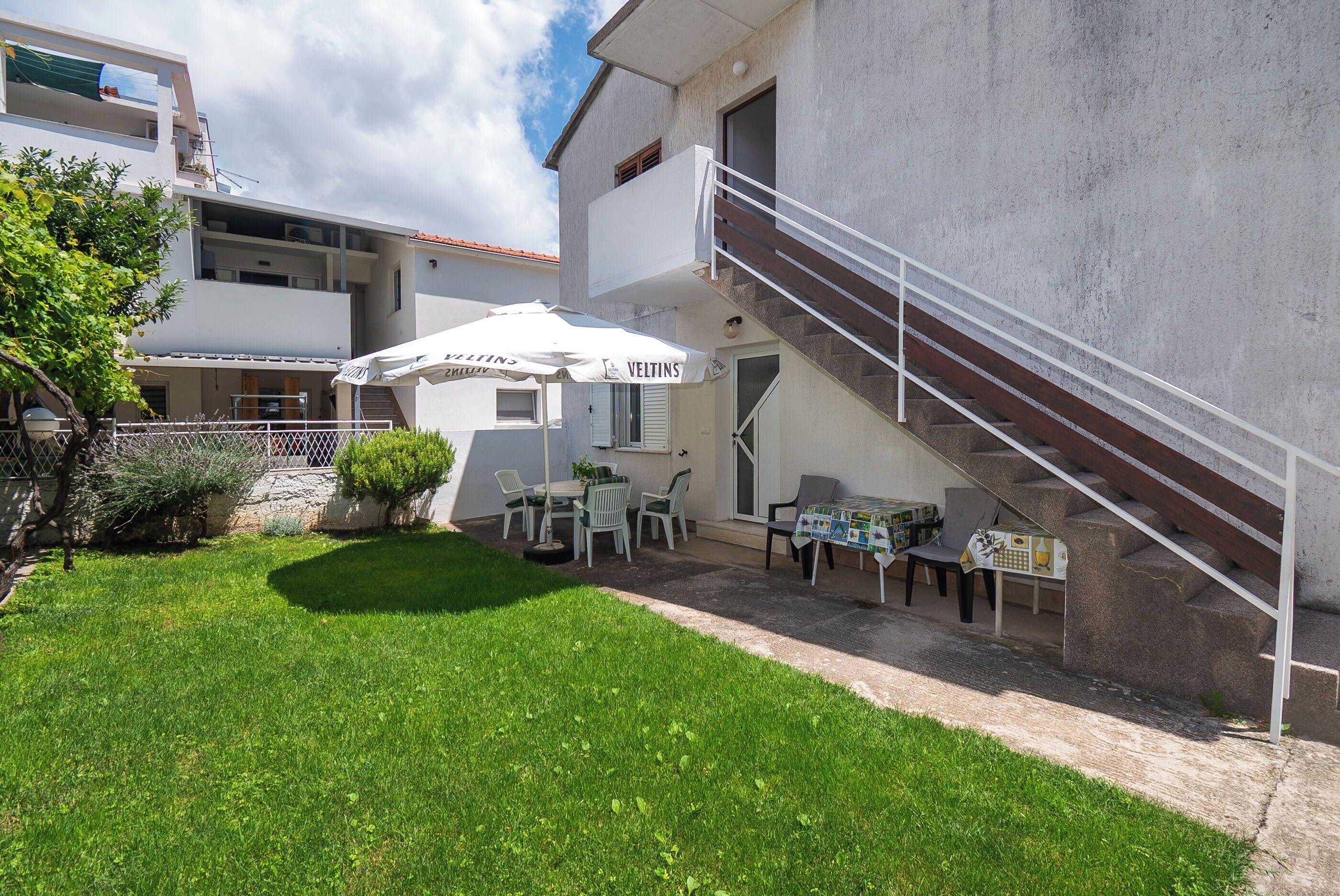 A courtyard with a dining area, outdoor seating, and a staircase leading to an upper floor.
