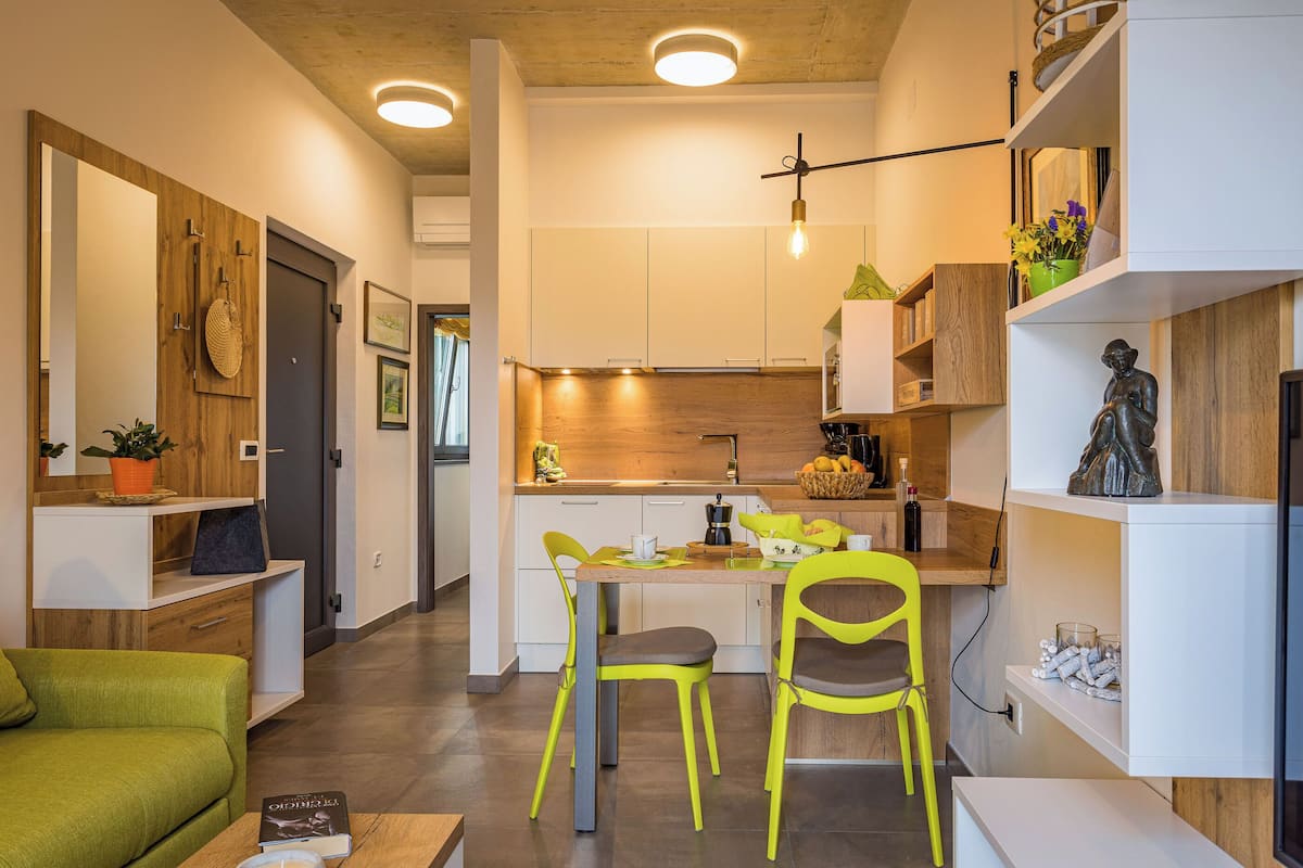 Eine moderne Küche mit weißen Schränken, einer Holz Arbeitsplatte und einem Essbereich mit zwei Stühlen.