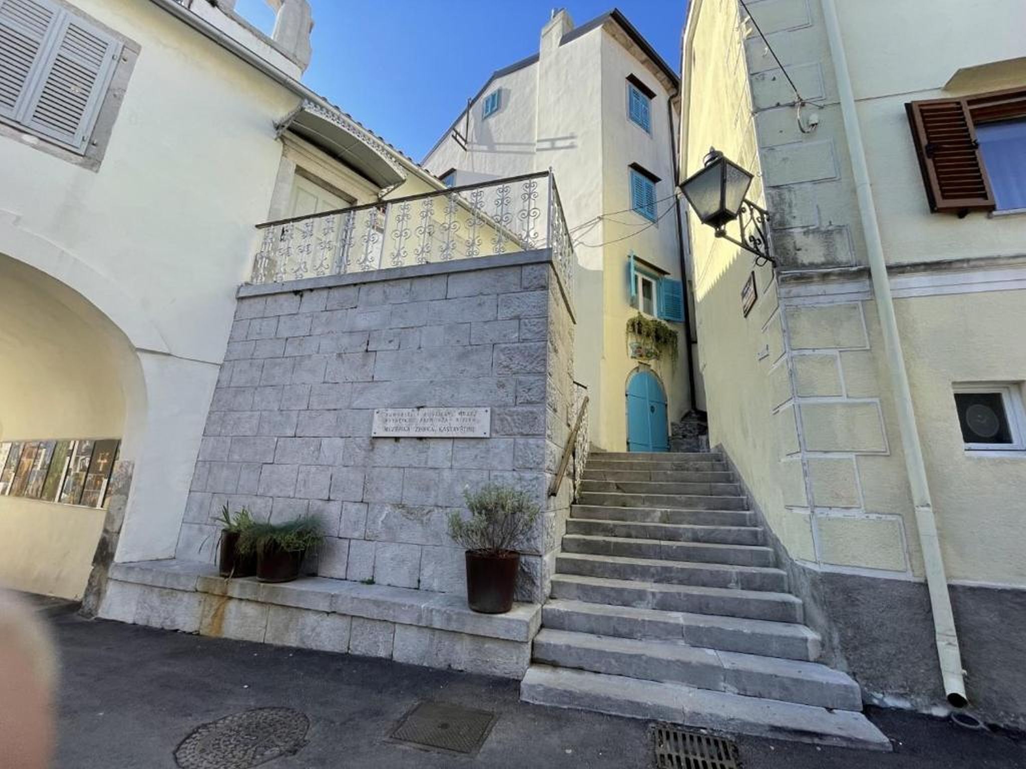 A narrow street with a stone staircase leading to a building with a blue door.