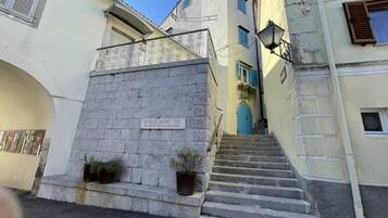 A narrow street with a stone staircase leading to a building with a blue door.