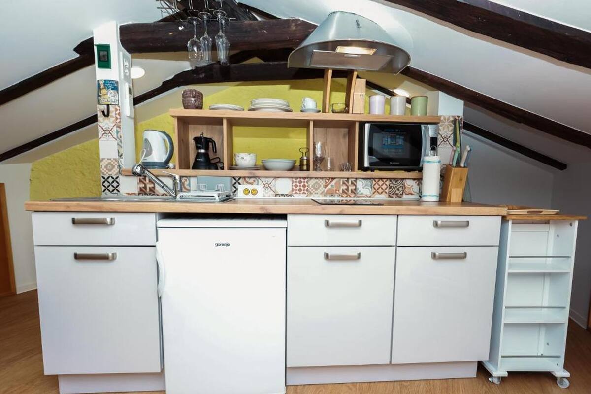Une cuisine compacte avec des meubles blancs, un four à micro-ondes encastré et un petit évier.