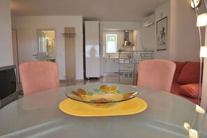 A modern living room with a glass dining table, a flat-screen TV, and a sofa. - Apartments Adrian (Rovinj)