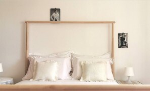 A neatly made bed with white linens and decorative pillows, a wooden headboard, and two bedside tables with lamps. - Apartments Marinic (Novalja)