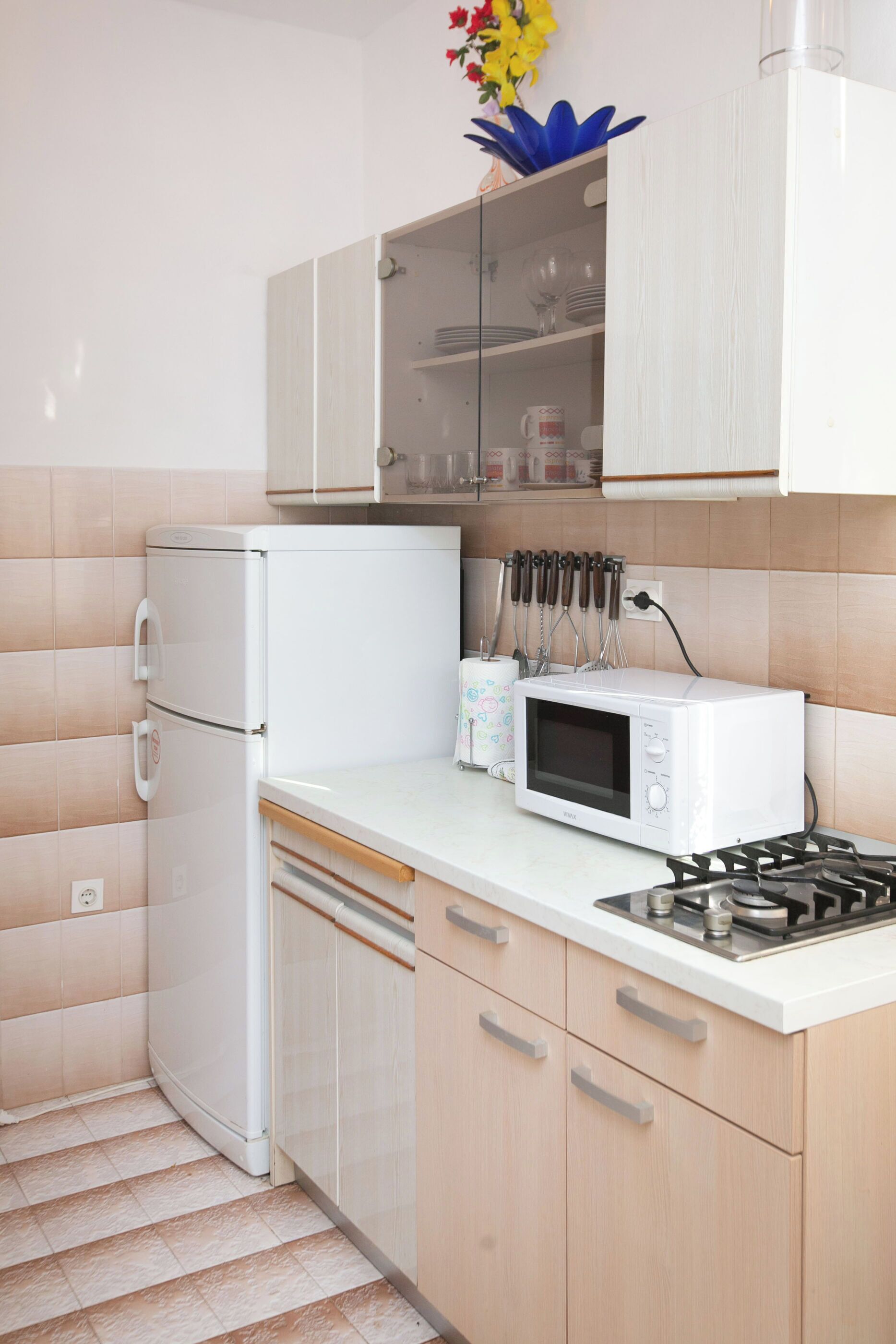 Una cucina compatta con un frigorifero bianco, un forno a microonde e un piano cottura a gas.