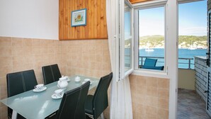 Un balcón con una mesa dispuesta para tomar té, vista al mar y una pared de madera con un marco de foto.