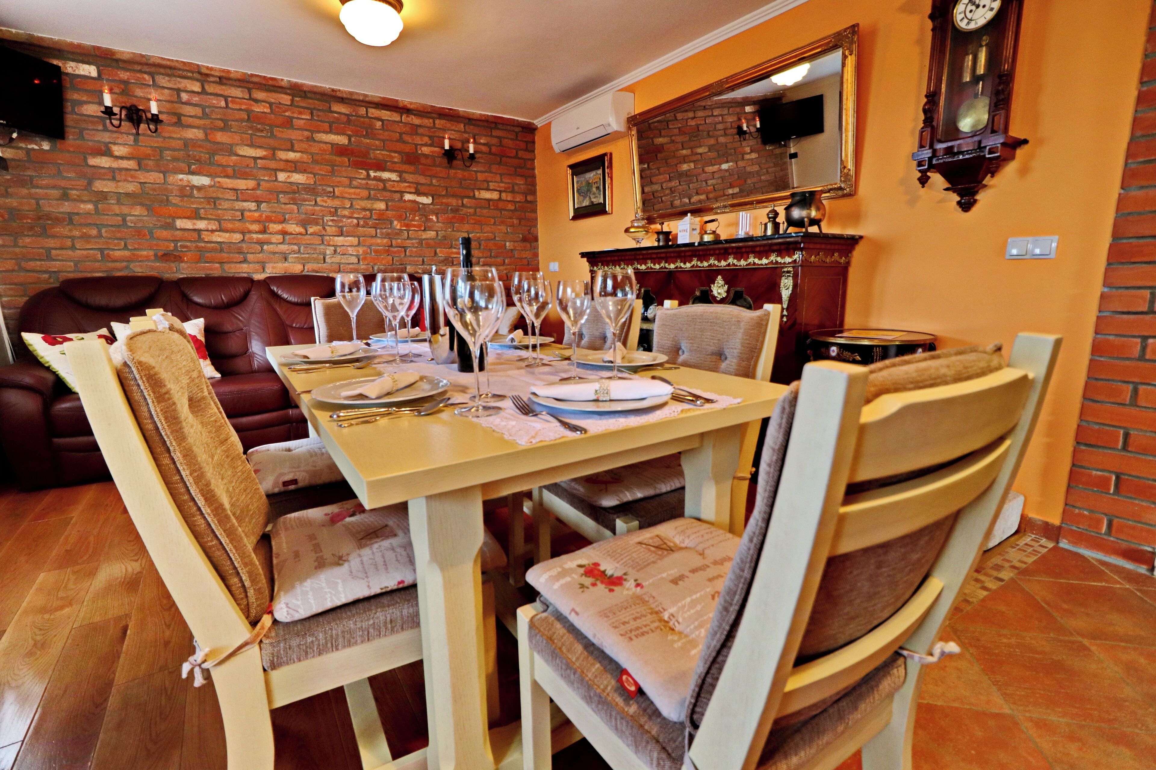 A dining area with a brick wall, a sofa, and a table set for a meal.