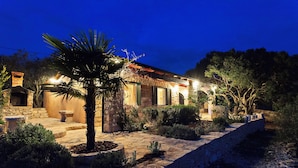 A stone building with a tiled roof, a stone staircase, and a well-lit entrance. - House Pelegrin (Vela Luka)