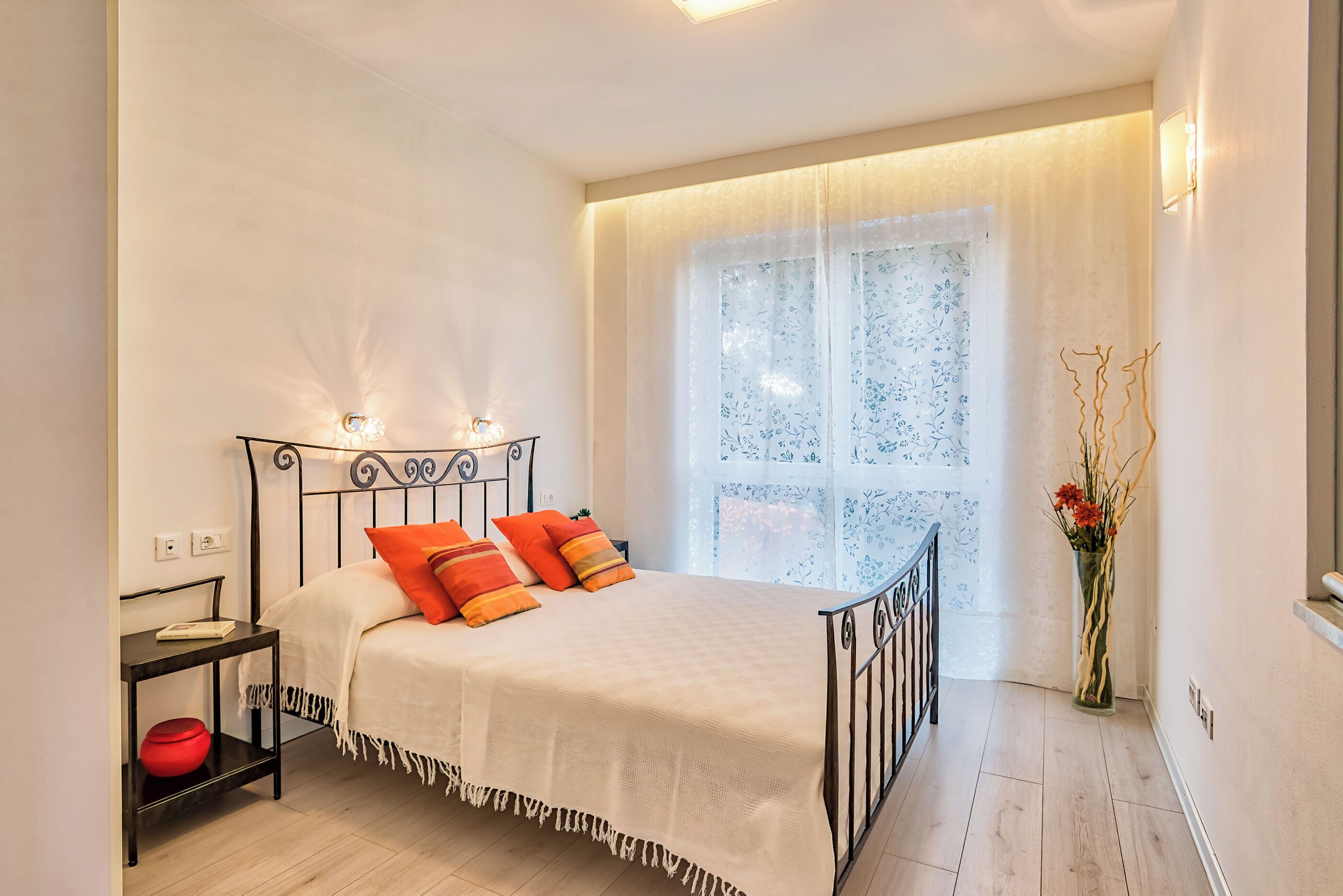 A bedroom with a bed, bedside table, and a window with curtains.