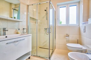 A modern bathroom with a glass-enclosed shower, a white sink, and a toilet. - Apartments Villa Sky (Rovinj)