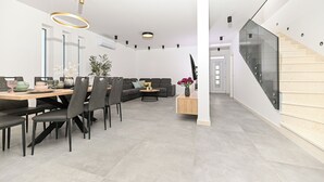 A modern interior with a dining area, sofa, staircase, and a glass railing. - Villa Flora (Kastela)