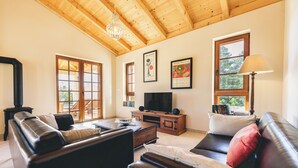 A living room with a wooden ceiling, a television, leather sofas, and a fireplace. - Villa Maslina (Marina)