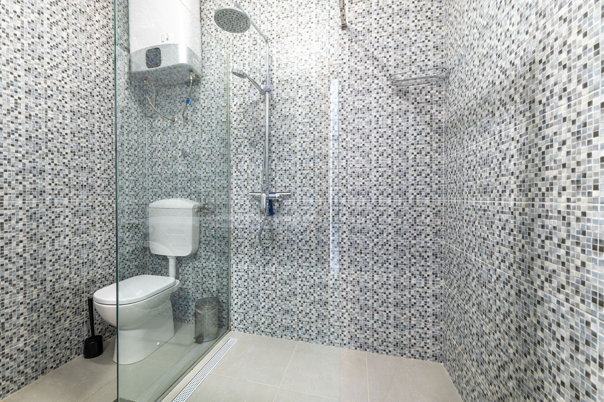 Une salle de bain moderne avec une douche à parois de verre, des toilettes et un mur recouvert de carreaux.