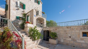 A stone building with a balcony, a staircase, and potted plants. - Villa Mare (Bol)
