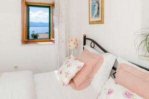 Une chambre à coucher avec un lit, une fenêtre donnant sur un beau paysage, une lampe et un tableau au mur.