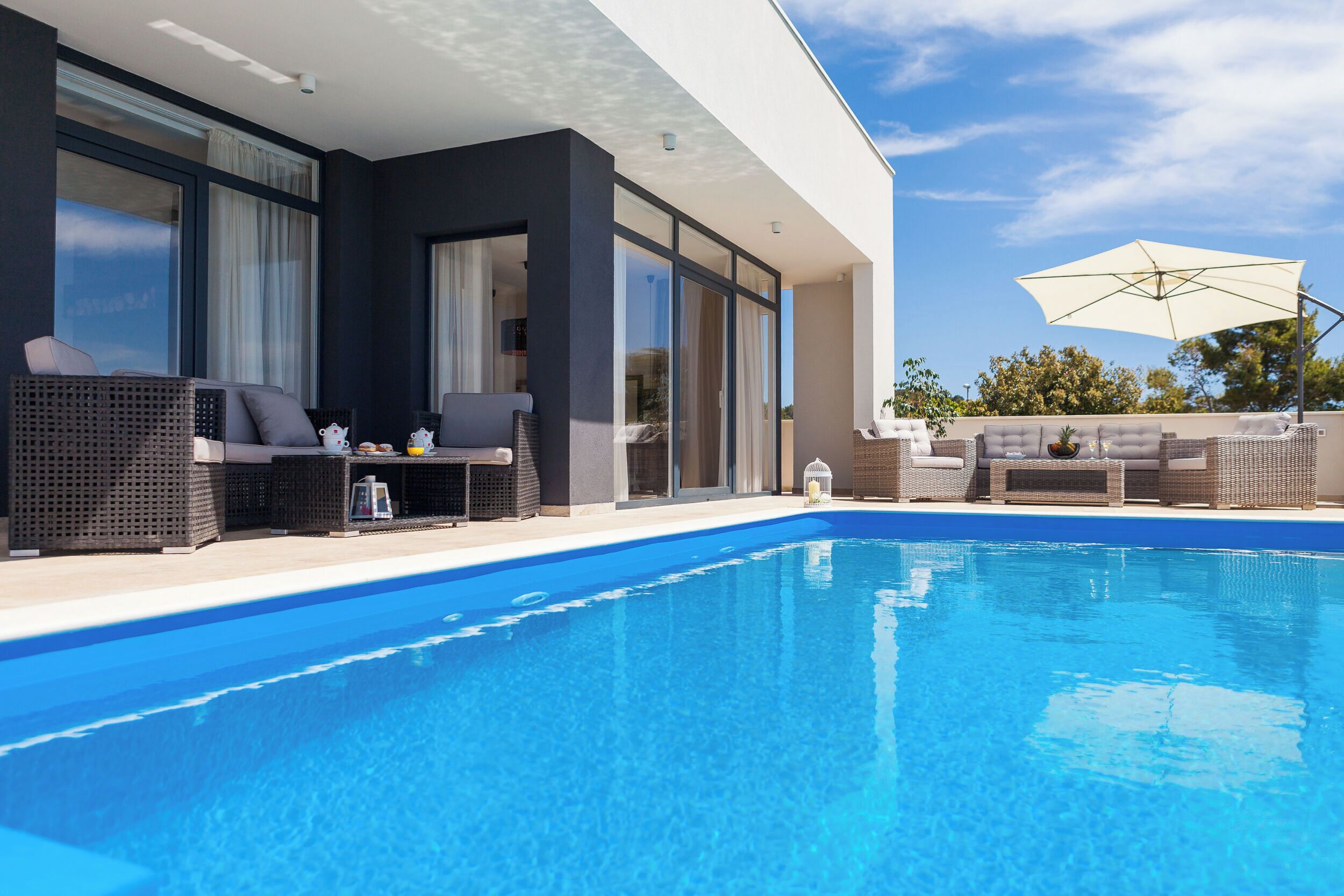 A modern poolside area with outdoor seating and a clear blue pool.