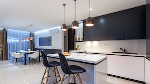Une cuisine moderne dotée d’un îlot central, de luminaires suspendus et d’un coin repas avec des chaises et une table.