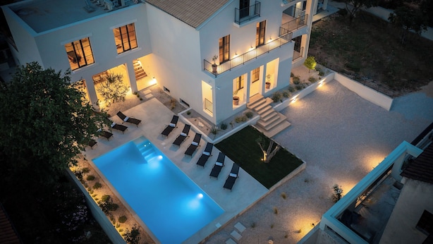 Una moderna casa a due piani con piscina, area salotto esterna e patio ben illuminato.