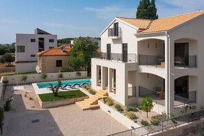 Ein modernes, zweistöckiges Haus mit Swimmingpool, Balkon und gepflegtem Garten.