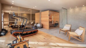 Una palestra moderna con attrezzature per esercizi, un pavimento in legno e una parete divisoria in vetro.