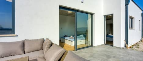 A modern building with a sliding glass door leading to a bedroom with a bed and a bench.