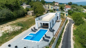 Ein modernes Haus mit Swimmingpool, Sitzgelegenheiten im Freien und Blick auf die umliegende Nachbarschaft.