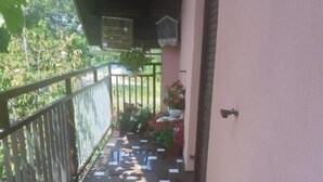 Un balcón techado con macetas y jaulas de pájaros colgantes.