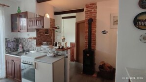 Una cocina con una isla central, armarios de madera, una pared de ladrillo y una chimenea.