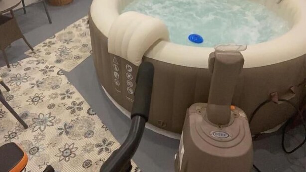 Un jacuzzi en una habitación con chimenea, un sillón y un tapete estampado.