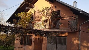 Una casa de dos pisos con balcón, chimenea y portón.