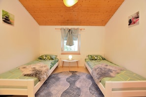 A small, cozy room with two single beds, a round rug, a small table, and a window with curtains. - Apartment Emilija (Fazana)