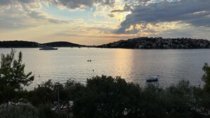 A calm lake with boats, a distant shoreline with buildings, and a cloudy sky. - Apartments Roza (Rogoznica)