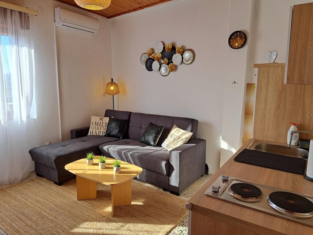 A modern living room with a sofa, a coffee table, and a kitchen area with a sink and countertop.