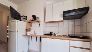 Una cocina compacta con un refrigerador blanco, una cafetera, un microondas y un lavamanos.
