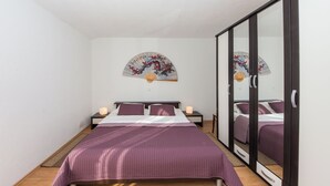 A bedroom with a bed, bedside tables, a mirror, and a decorative fan. - Apartment Yasmin (Vinodol)
