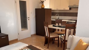 A modern living room with a sofa, a coffee table, and a dining area with a chair and a small table. - Apartment Yasmin (Vinodol)