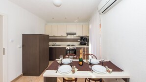 A dining area with a table set for four, a bottle of champagne, and a kitchen in the background. - Apartment Yasmin (Vinodol)