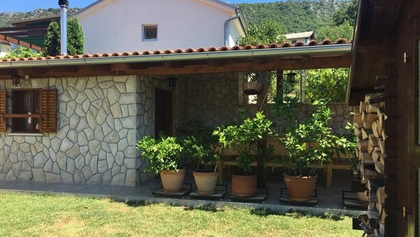 A house with a stone facade, a tiled roof, and potted plants in the front yard. - Apartment Yasmin (Vinodol)