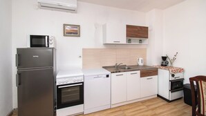 Μια μικρή, λειτουργική κουζίνα με ψυγείο, φούρνο μικροκυμάτων, κουζίνα, πλυντήριο πιάτων και καφετιέρα.