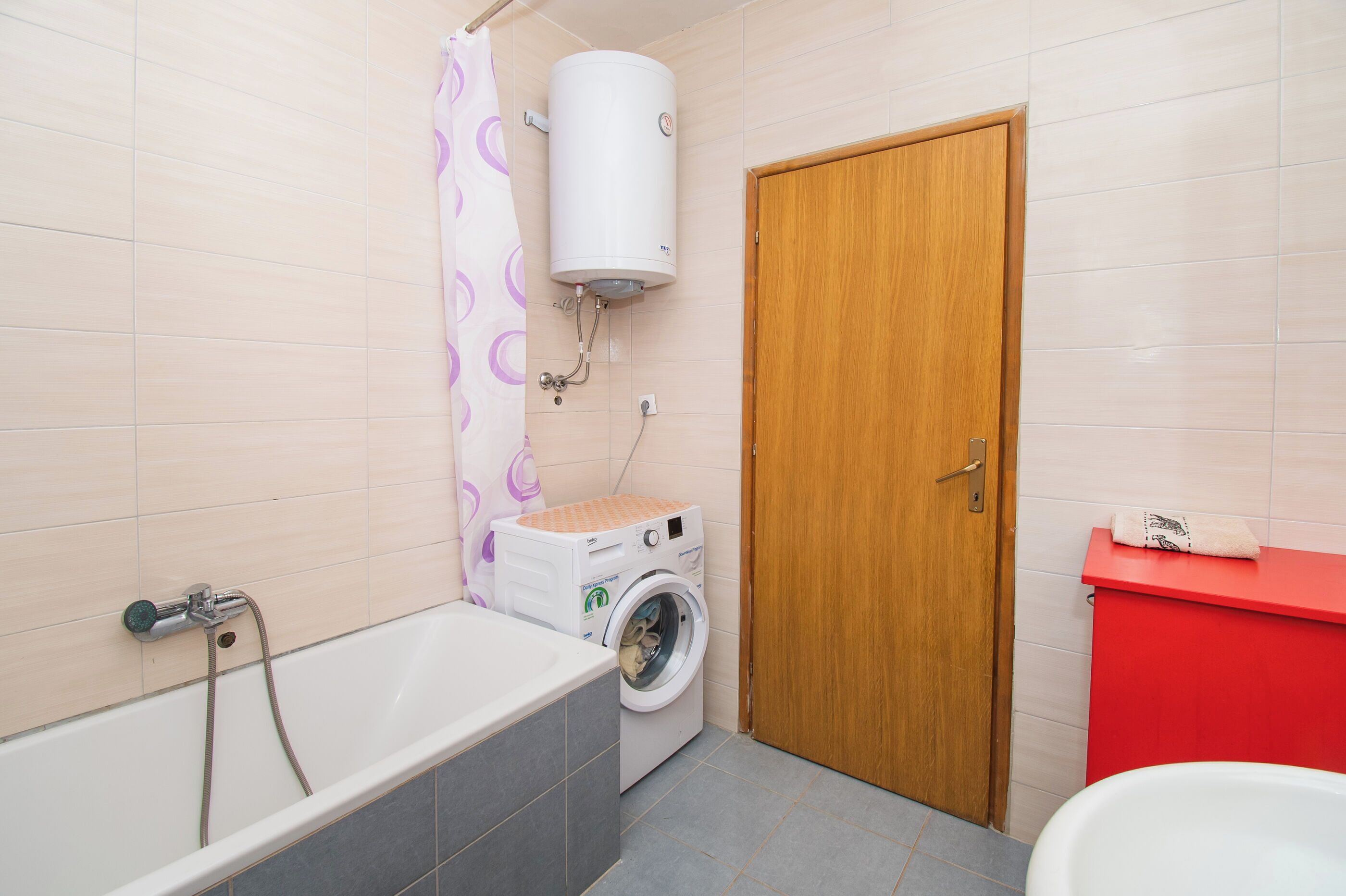 Un baño con bañera, lavadora, inodoro y cortina de ducha.