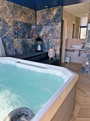 A modern bathroom with a marble wall, a bathtub, a sink, and a mirror. - Rooms Little Rock Center (Crikvenica)
