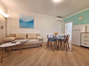 Un salon confortable avec un canapé, une petite table et un coin repas avec des chaises.