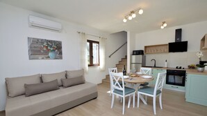 A modern kitchen with a dining area, a sofa, and a staircase. - House Danci (Vizinada)
