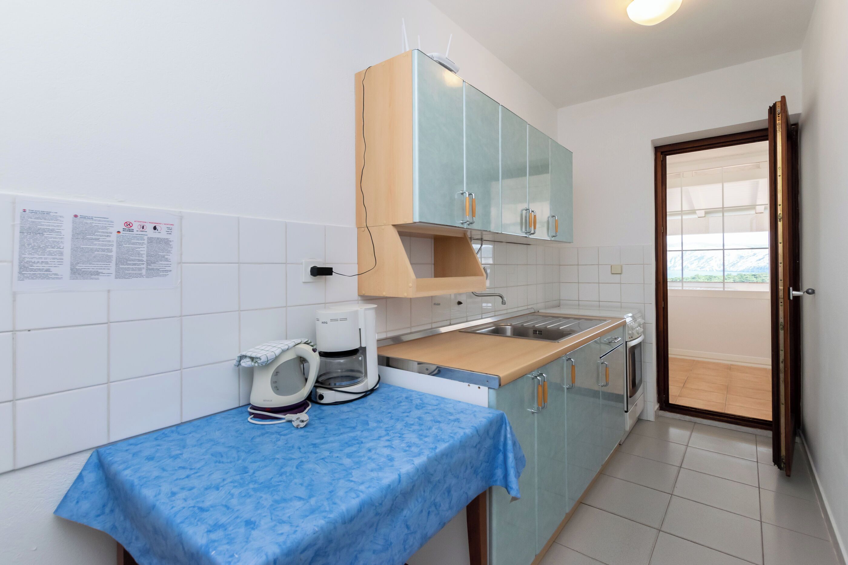 Una cocina compacta con mantel azul, cafetera y tostadora.