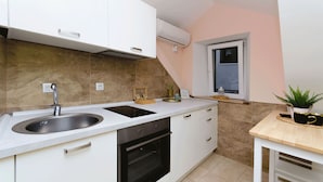 Eine moderne Küche mit Spüle, Herd und Backofen, weißen Schränken und einem kleinen Fenster.