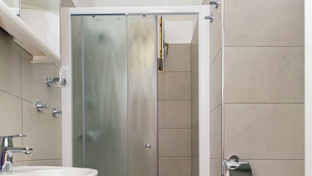 A modern bathroom with a glass-enclosed shower, a white sink, and a toilet. - Apartment Jele (Omis)