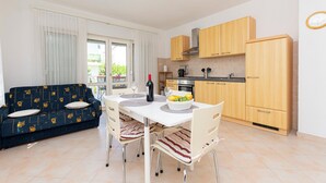A compact living space with a dining area, kitchenette, and a sofa. - Apartment Jele (Omis)