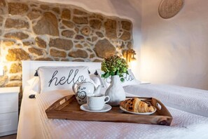 A neatly made bed with a tray containing a croissant, a cup of coffee, and a vase of flowers. - Apartment Filumena (Lopar)
