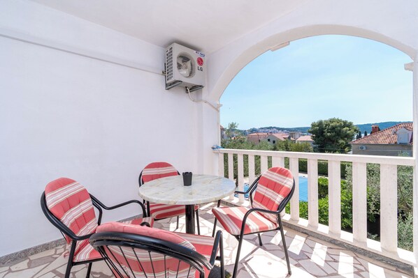 Un balcon avec une table et des chaises, un appareil de climatisation et une vue sur les environs.