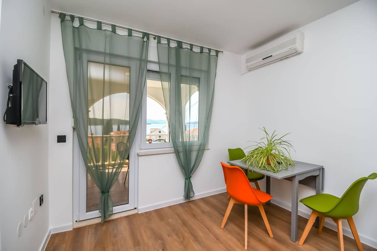 A room with a sliding glass door, a small table with a potted plant, and two chairs.